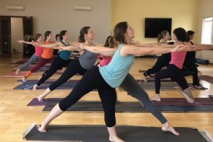Students moving through dynamic Vinyasa flow sequence connecting breath with movement
