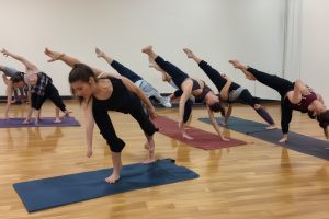 Advanced students performing challenging power yoga sequences requiring strength and balance